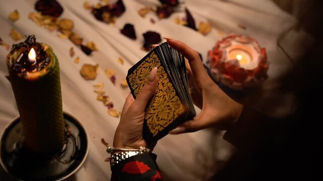 Close-up of witch hands shuffling deck of tarot cards. Magic sessions with cards. A close up of mystical tarot deck of cards.