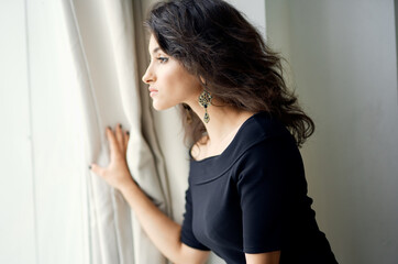 Naklejka premium Woman in black dress near the window fashionable hairstyle decoration luxury