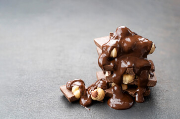 melted chocolate spread with hazelnut on black background. Chocolate tower covered with topping. recipe For making chocolate with nuts. Cooking handmade chocolate bar, dessert, candies. Confectionery