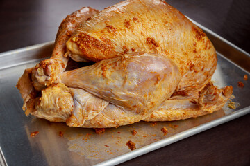 Baking sheet with raw turkey on wooden table.
