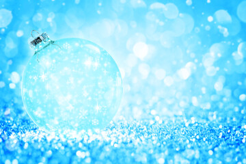 Fototapeta na wymiar Transparent Christmas ball with snowflake against glitter bright blue background.