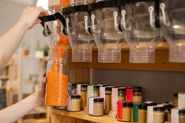 A man fills a jar with red lentils. Selling bulk goods by weight in an eco store. Trade concept...