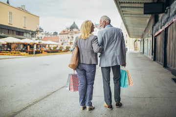 Fototapeta na wymiar Senior couple carrying shopping bags and enjoying to shopping