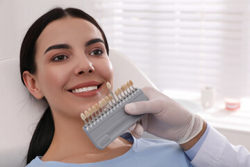Dentist checking young woman's teeth color in clinic