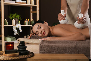 Young woman receiving herbal bag massage in spa salon