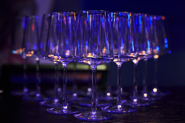 beautiful transparent wine glasses displayed on the table and illuminated in blue. serving empty glasses