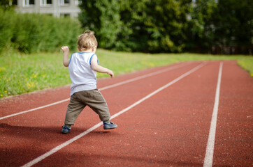 Fototapeta premium person running on the track, one year baby walking on the running track in the school playground