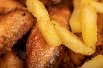 Fried chicken wings and French fries on a plate, close-up, selective focus.