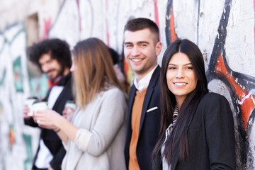 Friends having fun time outdoors. Group of people posing on a wall with old abstract unrecognizable grafitti.