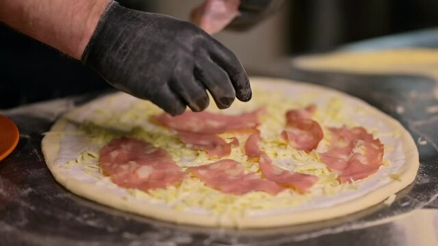 Process of making pizza in restaurant. Process of making traditional italian pizza. Chief putting hamon and cheese on it