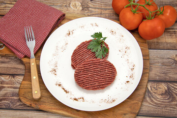 deux steaks hachés de boeuf crus dans une assiette