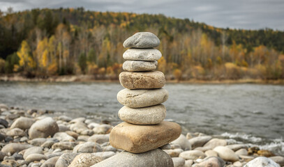 Pile of stones built in cairn on the background of river. Calmness and detachment with nature
