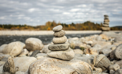 Pile of stones built in cairn on the background of river. Calmness and detachment with nature