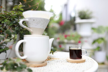 White coffee cup and ceramic coffee drip pot on metal tablet at outside