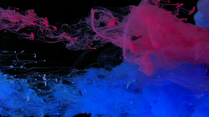 Drops of pink and blue ink in water. Pink and blue watercolor paints in water on a black background. Awesome abstract background. Beautiful wallpaper for your desktop.