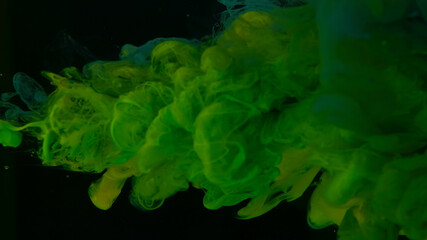 Cosmic star background. Green and yellow watercolor paints in water on a black background. Beautiful wallpaper for your desktop. Green and yellow cloud of ink. Awesome abstract background.