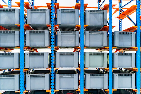 plastic boxes in the cells of the automated warehouse. Metal construction warehouse shelving