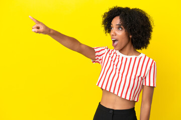 Young African American woman isolated on yellow background pointing away