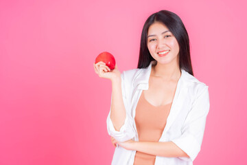 Obraz na płótnie Canvas beautiful Asian woman cute girl feel happy holding red apple fruit for good health isolated on pink background with copy space - lifestyle healthy woman concept
