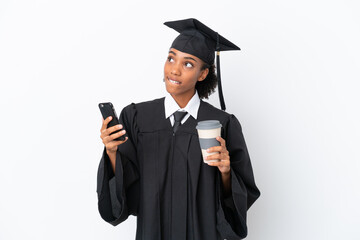 Young university graduate African American woman isolated on white background holding coffee to take away and a mobile while thinking something