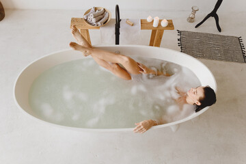 Beautiful woman relaxing in bathtub with foam.