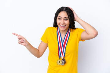 Teenager girl with braids and medals over isolated pink background surprised and pointing finger to the side