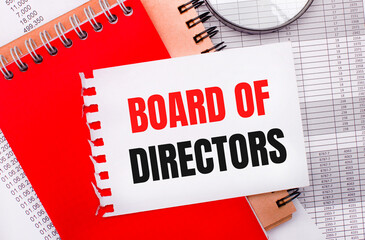 On a light background - reports, a magnifying glass, brown and red notepads, and a white notepad with the text BOARD OF DIRECTORS. Business concept