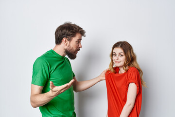 a young couple multicolored t-shirts communication quarrel light background