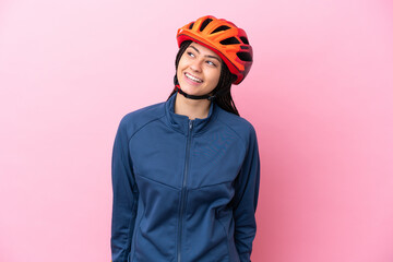 Teenager cyclist girl isolated on pink background looking to the side and smiling