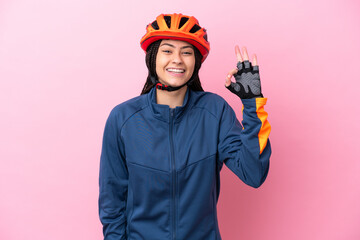 Teenager cyclist girl isolated on pink background showing ok sign with fingers