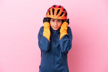 Teenager cyclist girl isolated on pink background frustrated and covering ears