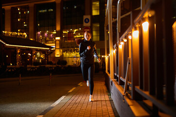 Beautiful Slim Fitness Woman in Black Athletic Wear is Jogging In Night City Street. Female is Doing Workout at Night Alone,Young Redhead Lady Enjoy Being Healthy And Sporty, Preparing For Marathon