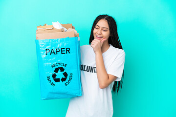 Teenager girl with braids holding a bag to recycle looking to the side and smiling