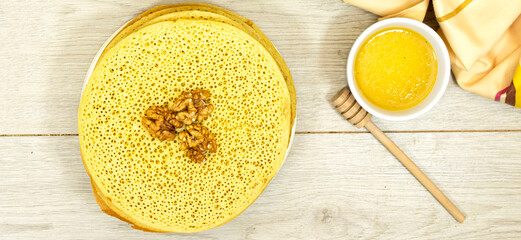 Moroccan or Algerian pancakes named Baghrir in arabic on wood table with homey syrup bowl