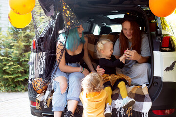 Diverse family friends celebrating Halloween in car trunk outdoors