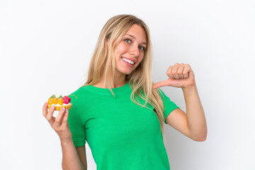 Young caucasian woman holding a tartlet isolated on white background proud and self-satisfied