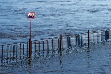 Prohibitory sign on a flooded city river embankment. The inscription in Russian: Swimming is prohibited.