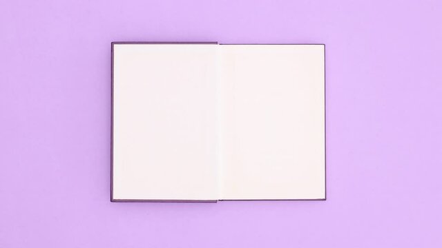 Dark purple hardcover book appear on purple background and open. Stop motion