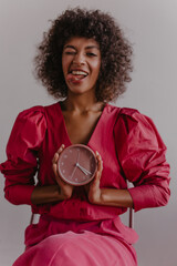  pretty naughty African woman shows her tongue pressed between her teeth while sitting on chair on...