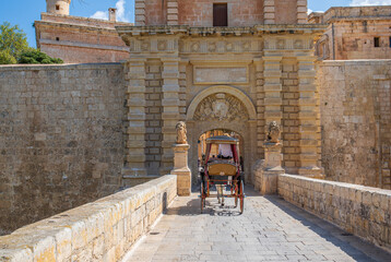 Fototapeta na wymiar Mdina Malta the gated main entrance with a horse drawn carriage going over the stone bridge