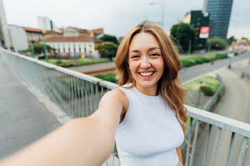 Young caucasian woman outdoor taking selfie smiling happy or doing videocall - obrazy, fototapety, plakaty