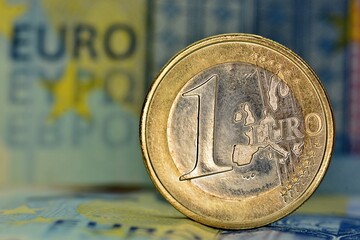 Moneda de 1 euro con fondo de un billete de 20 euros