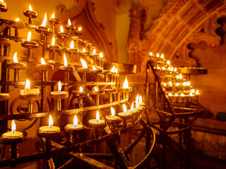 Lit candles in racks in a historic church