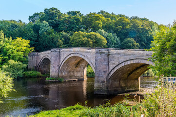 A view towards a medieval road bridge over the River Tees at Piercebridge, UK in summertime