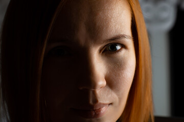 The face of a red-haired woman of middle age 40 years old close-up. She looks into the camera.