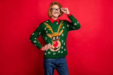 Photo of charming pretty young man wear green sweater arm spectacles smiling isolated red color...