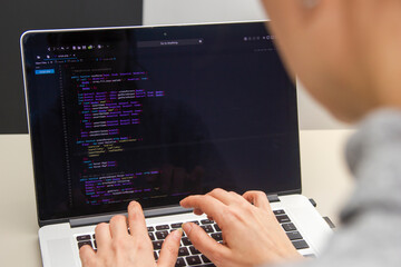 A programmer coding on a laptop in the workplace