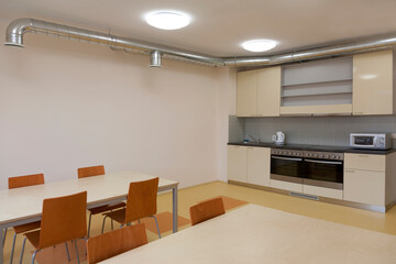Modern youth hostel building.  Kitchen and eating areas. Two ovens, kettle and toaster.