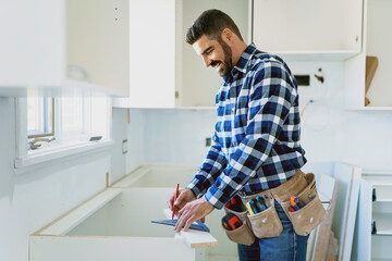 Concentrated young man work with white cabinet in the kitchen