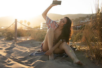 Happy young woman relaxing on the sandy beach. Beautiful woman listening the music...